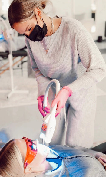Person receiving dental treatment with a dental tool, wearing a face mask and gloves.