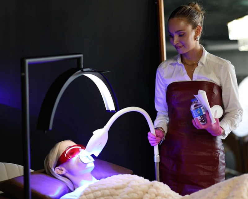 Person receiving LED light therapy with a therapist holding a device.
